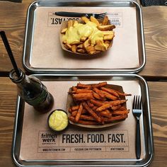 two trays with food on them sitting on top of a table next to each other