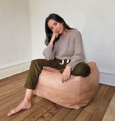 a woman sitting on a bean bag chair in the middle of a room with wood flooring