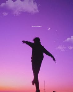 a person is flying a kite in the air at sunset or dawn with a purple sky behind them