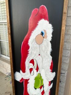 a painting of santa clause holding a candy cane in front of a door that says merry christmas