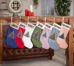 christmas stockings hanging on a rail in front of a table with candles and other decorations