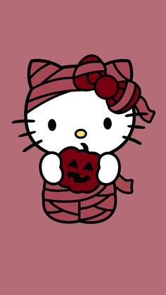 a hello kitty holding a pumpkin in her hand and wearing a knitted scarf on top of it