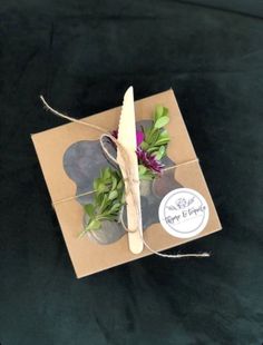 a box with some flowers and a knife in it on a black tablecloth covered surface