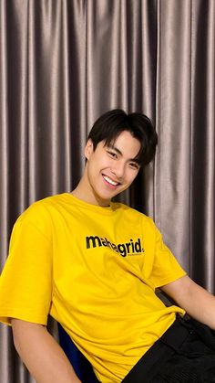 a young man sitting on top of a blue chair wearing a yellow t - shirt