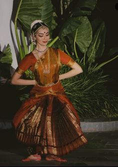 a woman in an orange and gold dress dancing