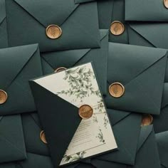 green envelopes with gold buttons and a wedding card in the middle, surrounded by other dark green envelopes