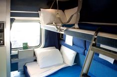 there is a bunk bed on the train with blue sheets and white pillows in it