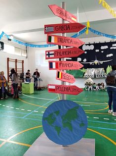 a group of people standing around a room with flags and signs on the floor in front of them