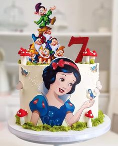 there is a cake decorated with the characters of snow white and seven dwarfs on it