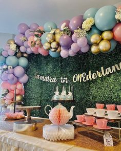 a table with balloons, teapots and other items on it in front of a backdrop