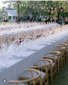 a long table is set up with white linens and pink flowers in vases