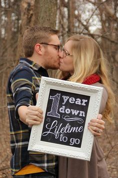 a man and woman kissing while holding a sign