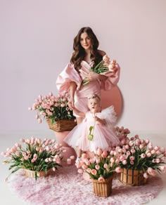 a mother and her daughter are posed in front of pink tulips with flowers