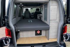 the back end of a van with its cargo door open and seats folded up in place