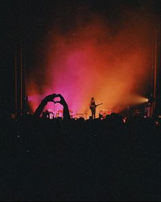 a person standing on top of a stage in front of purple and red lights at night