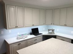 a kitchen with white cabinets and a laptop on the counter