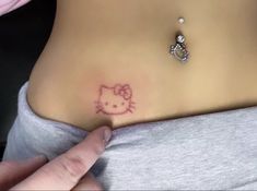 a hello kitty tattoo on the side of a woman's stomach is shown in pink ink