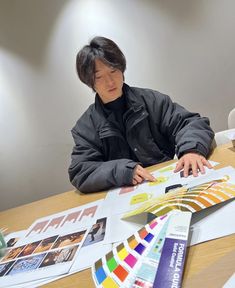 a person sitting at a table with some papers and paint swatches on top of it