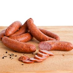 several sausages on a wooden cutting board with peppercorin and seasoning nearby