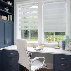 a white office chair sitting in front of a window next to a desk with a computer on it