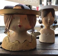 two ceramic figurines sitting on top of a wooden table next to each other