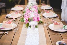 the table is set with pink flowers and birdcage place settings for guests to eat