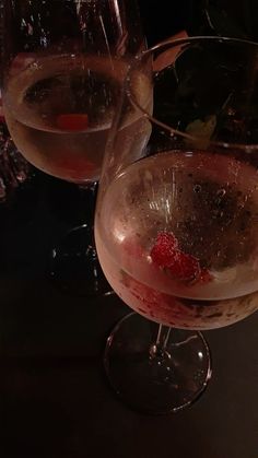 two wine glasses filled with pink liquid and strawberries