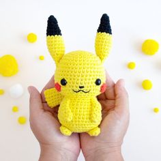 a hand holding a small yellow crocheted pikachu