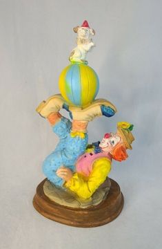 a figurine of two clowns on top of a ball with a man