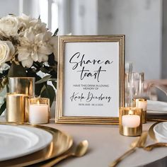 a table with white flowers and gold place settings on it, along with a framed sign that says shorea feast