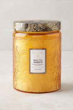 a yellow jar filled with liquid sitting on top of a white tablecloth covered floor