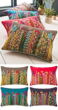 four pillows with different designs on them sitting on a table next to a potted plant