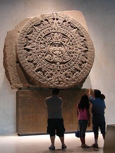 three people standing in front of a large stone object that is on display at the national anthropy museum, mexico city