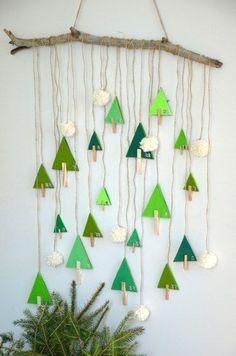 a green and white christmas tree mobile hanging on a wall next to a potted plant