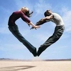 two people in the air making a heart shape with their hands while standing next to each other