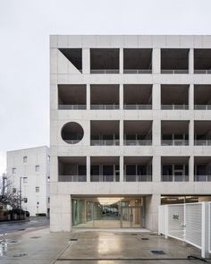 an empty parking garage in front of a large white building with balconies on the second floor