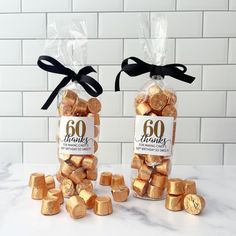 two bags filled with gold foiled chocolates on top of a marble countertop