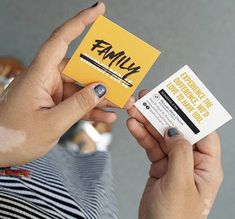 a woman holding up a business card with the word family on it in front of her