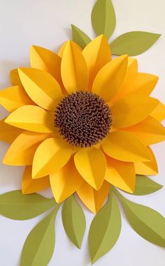 a paper sunflower with green leaves on the bottom and yellow petals on the top