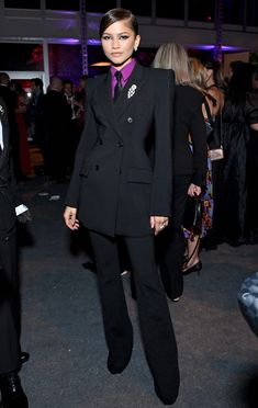 a woman in a black suit and purple tie