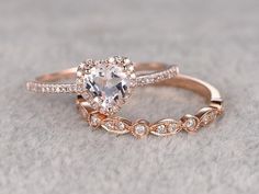 two rose gold wedding rings with an oval cut diamond in the center and side stones on each band