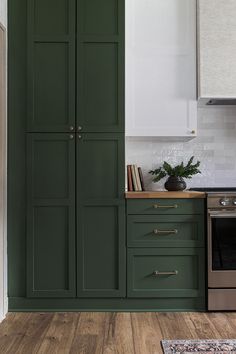 a kitchen with green cupboards and an oven in the center, along with a rug on the floor