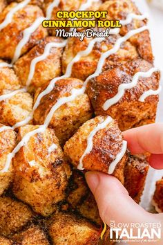 a close up of a person holding a cinnamon roll with icing on it and the words crockpot cinnamon roll market bread