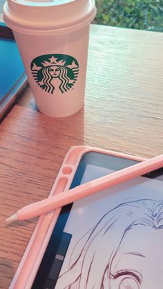 a cup of coffee next to a tablet with a drawing on it and a pink pen