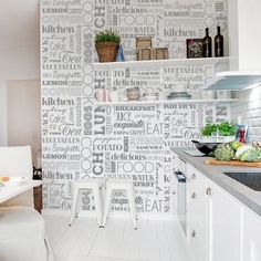 a kitchen with white cabinets and walls covered in words