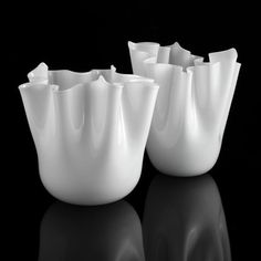 four white vases sitting on top of a black table