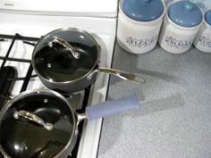 pots and pans sitting on top of an oven with blue liquid in the middle