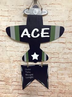 a sign that says ace on the side of a brick wall with two small signs attached to it