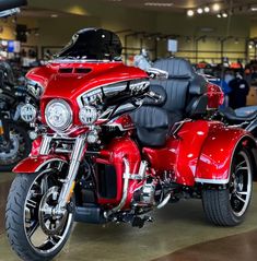 a red motorcycle is parked in a showroom with other motorcycles and people looking at it