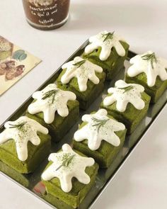 there are many green squares with white icing on them and some other food items